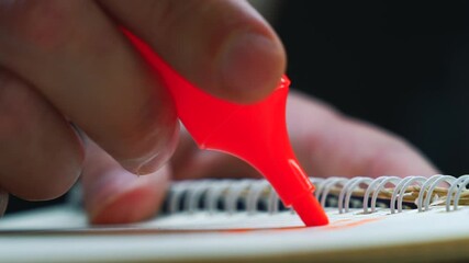  orange marker is in the hands of a student who is crossing out something in a notebook.
A man uses a colored felt-tip pen to study.
Using highlighter in studies