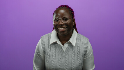 Obraz premium African american woman smiling with hands up against isolated purple background wearing glasses and grey sweater.