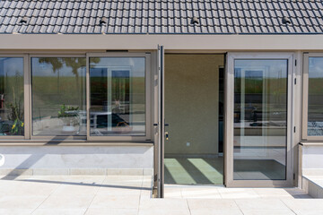Véranda moderne lumineuse avec baies vitrées et mobilier contemporain, ouverte sur un jardin...