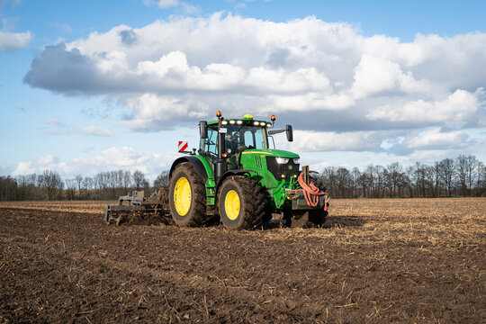 Ackerbau - Traktor John Deere 6215 R mit Grubber beim Einarbeiten von G&uuml;lle in den Boden.