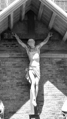 Dark artistic cross on a shaded rough textured brick wall