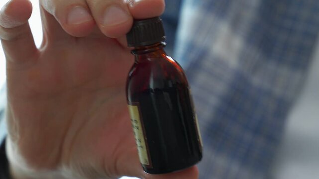 A man shakes a brown glass jar of iodine.
Use of iodine for medical purposes.
Yob in a bottle close up