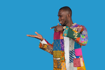 Stylish man pointing and showing with open hand on blue background