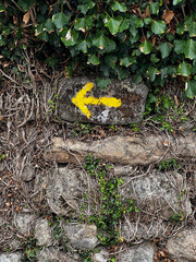 yellow arrow sign pointing left in portugal on the camino de Santiago, the road to santiago, christian pilgrimage in Spain and portugal