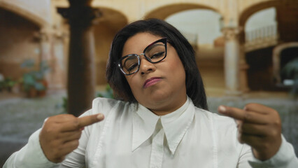 Young woman at an old university courtyard displaying a defiant expression in outdoor setting, capturing the essence of cultural heritage and modern attitude.