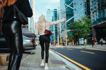 Two women walking on city street and catches car, summer Seoul