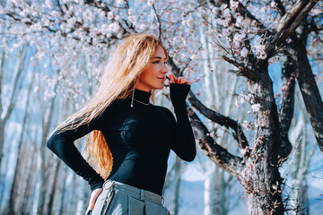 Romantic portrait of woman smelling flower under blooming tree