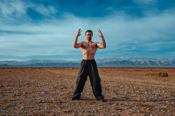 Young strong man martial arts training in the mountains on summer day