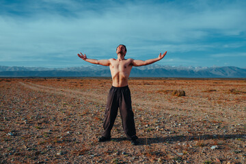 Young strong man sports training in the mountains on summer day