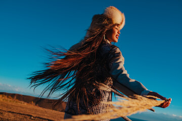 Young traditional kyrgyz woman portrait on blue sky background at sunset light