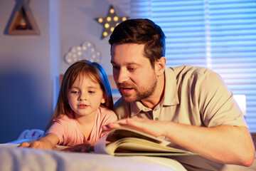 Obraz premium Father reading bedtime story to her daughter at home