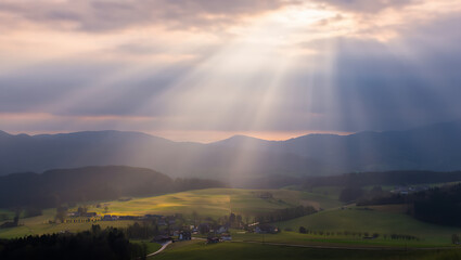 Dramatic mountain landscape at sunrise or sunset, featuring a panoramic view of misty hills and cloud-kissed peaks under a vibrant sky
