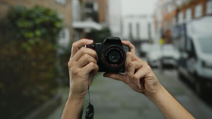 Man holding camera in urban street with blurred city background capturing the essence of photography and technology outdoors in a modern city environment.