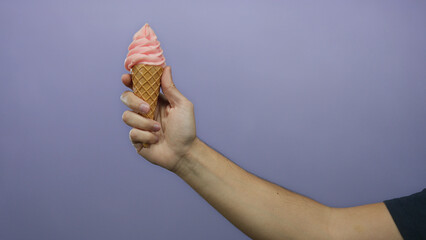 Man hand holding ice cream cone against purple wall showcases a casual moment with a refreshing...