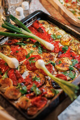 Freshly roasted zucchini and red pepper dish garnished with green onions and parsley on a serving tray