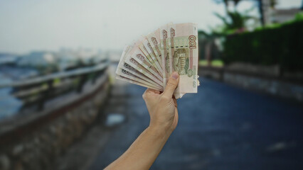 Man holding russian ruble banknotes in an outdoor street setting, showcasing currency exchange or...