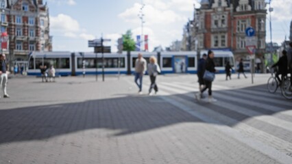 Obraz premium Blurred people crossing a street in a bustling european city with iconic architecture and a tram in the background, illustrating urban daily life and movement.