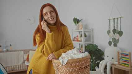Woman talking on phone in laundry room with basket of clothes wearing yellow sweater with home decor in background showing relaxing environment.