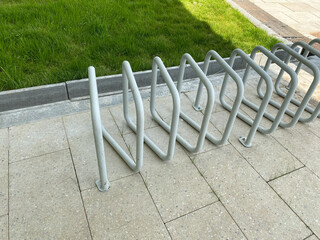 Bike parking stand in urban park. Contemporary white metal bicycle rack with smooth curves.