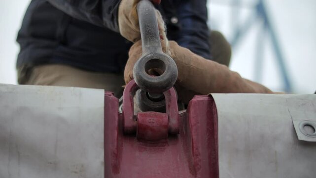 Worker attaching lifting shackle to cargo hook