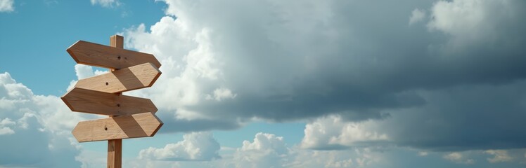 Wooden signpost against sky with clouds. Guidepost with direction arrows show different ways. Symbol of choice, decision making, travel, freedom, exploration, new opportunities crossroads. Ideal for