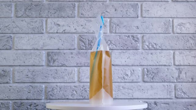 Lemon beer in plastic bag, rotating on turn table, side view. Adult alcoholic drink in spill-proof disposable drink pouch. Perfect format for party, picnics and walks.