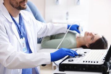 Sonographer conducting ultrasound examination of woman's thyroid gland in clinic, closeup