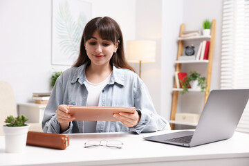 Woman using modern tablet at desk indoors