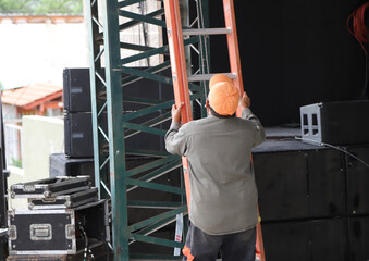 
Worker climbing ladder during stage assembly
