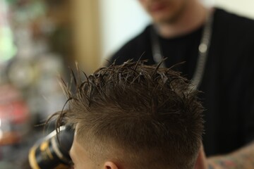 Professional barber working with client in barbershop, closeup