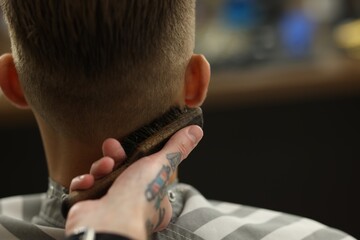 Professional barber working with client in barbershop, closeup. Space for text