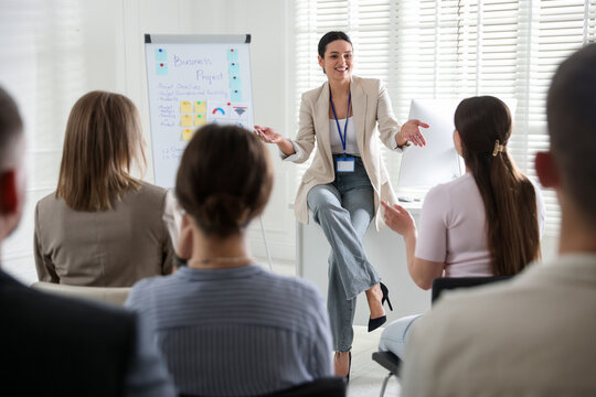 Woman giving public speech in front of audience indoors