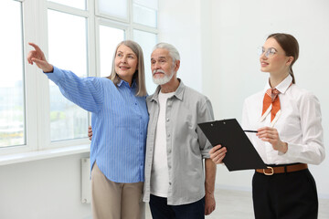 Smiling real estate agent with clipboard and couple at home
