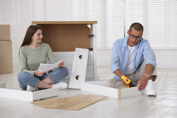 Happy couple assembling furniture on floor at home
