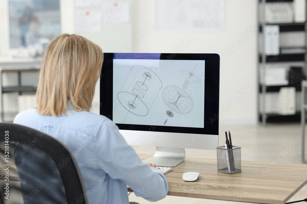 Poster technician making digital engineering drawing on computer at desk in office, back view