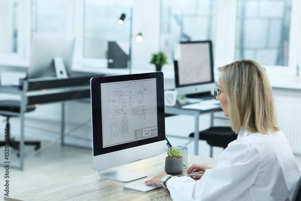 Poster technician making digital engineering drawing on computer at desk in office