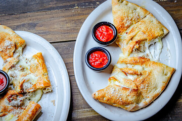 Stromboli stuffed with cheese and pepperoni served with a side of ketchup cups.