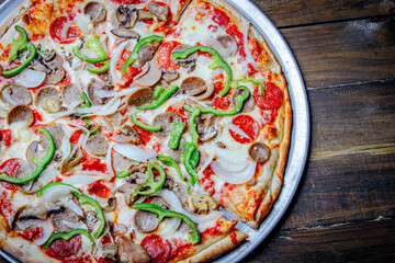 Meat and vegetables pizza served in a round pan 