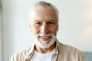 Portrait of a smiling senior man with white beard showing positive emotions