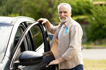 Senior man with blue ribbon opening car door