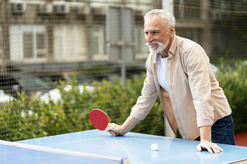 Senior man playing ping pong outdoors having fun and smiling