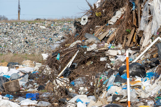 Mounds of plastic waste and debris tower over the landscape at a landfill, showcasing the growing problem of waste management and pollution in urban settings