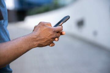 A man is focused on texting on his smartphone while enjoying the outdoors, portraying connection and modern communication. close up,selective focus on hand while using phone