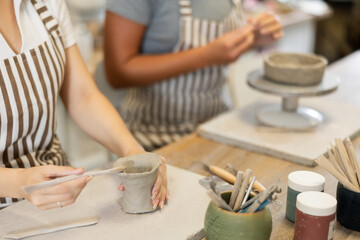 Female hands sculpting product from raw clay in ceramic workshop close-up