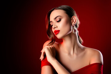 Portrait of a glamorous young woman in a red dress with elegant makeup and luxurious jewelry...