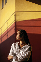 Fototapeta premium Young hispanic woman in white shirt posing against colorful urban wall