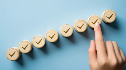 Seven wooden tokens with checkmarks increase in size on a blue background as a hand presses the largest, symbolizing progress and achievement in a smooth ascending line
