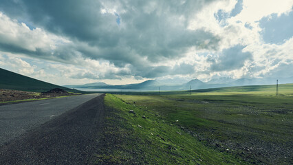 Scenic road winding through green fields and mountains