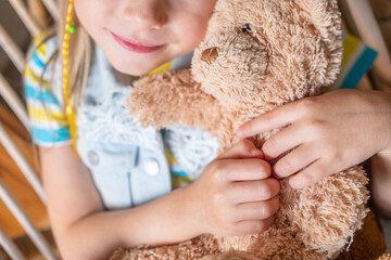 little child, preschool girl 5 years old plays with toy, hugs teddy bear, happy childhood,...