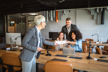 Confident senior businesswoman share documents with colleagues